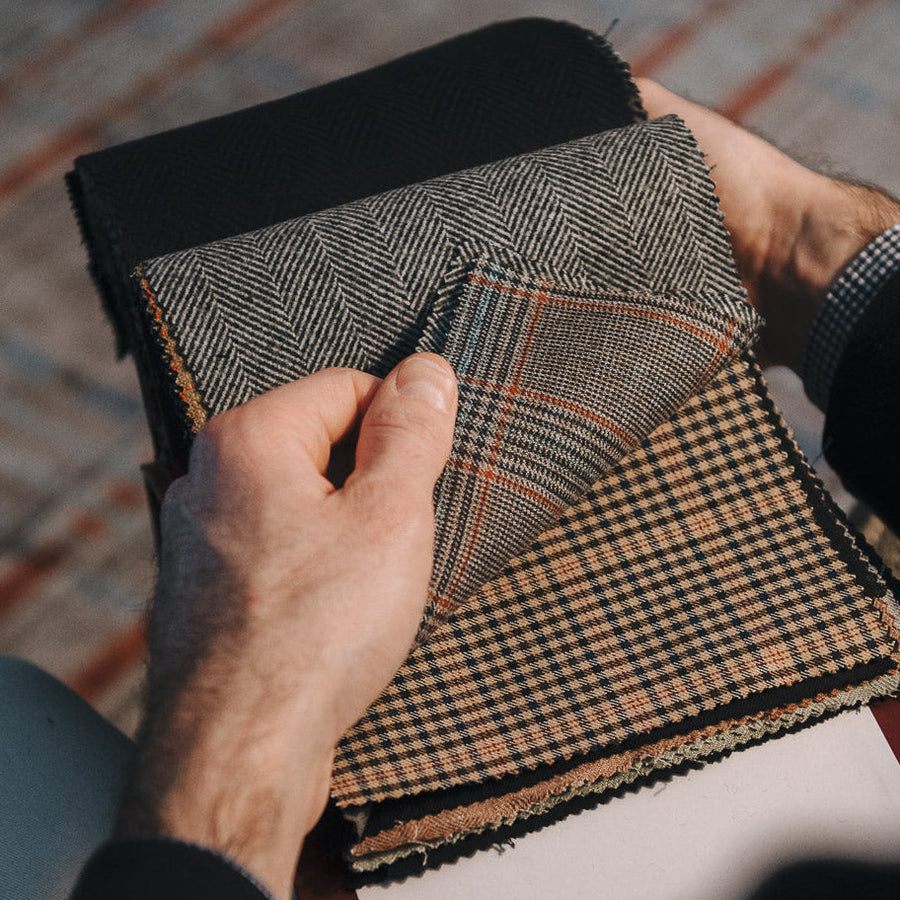 Person holding a swatch of plaid fabric with a blurred background