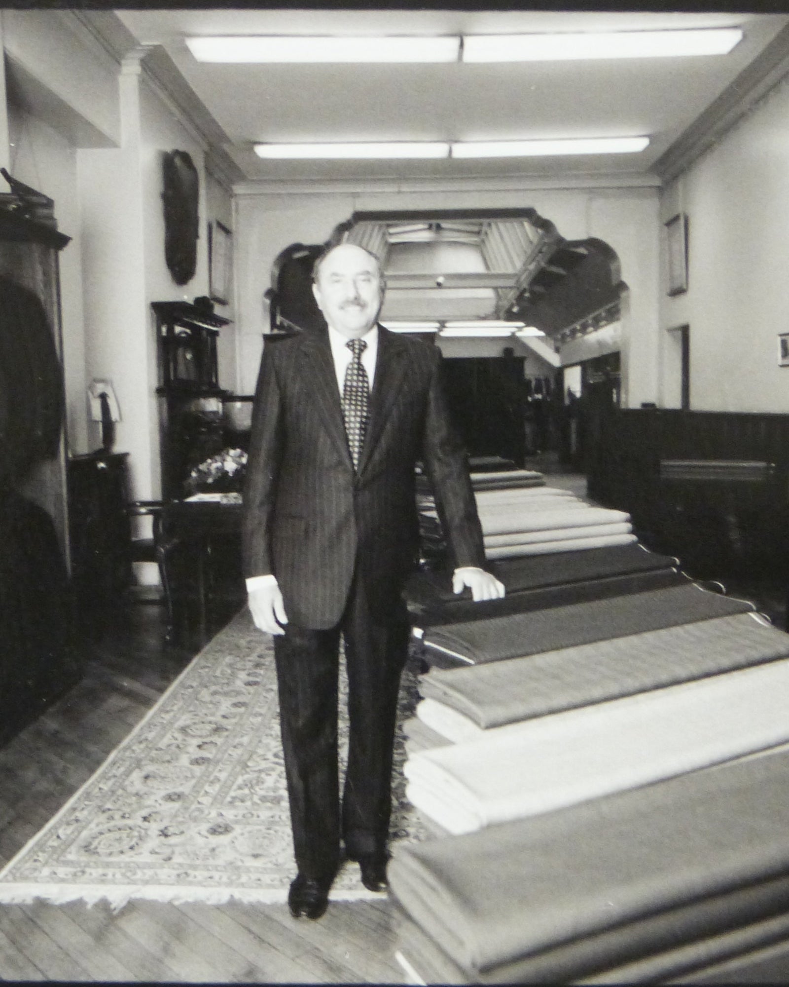 Man standing in Huntsman shop with stacks of cloth