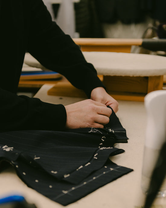 Huntsman tailor sewing baste garment in the workroom at 11 Savile Row
