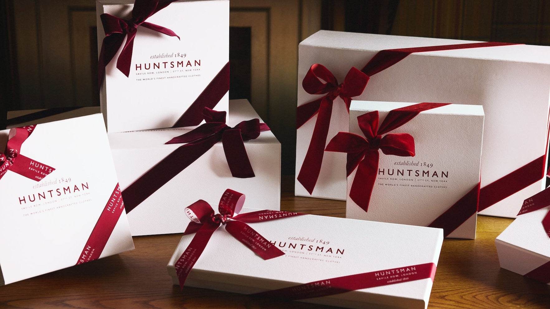 Gift boxes with red ribbons and 'Huntsman' branding on a wooden surface.