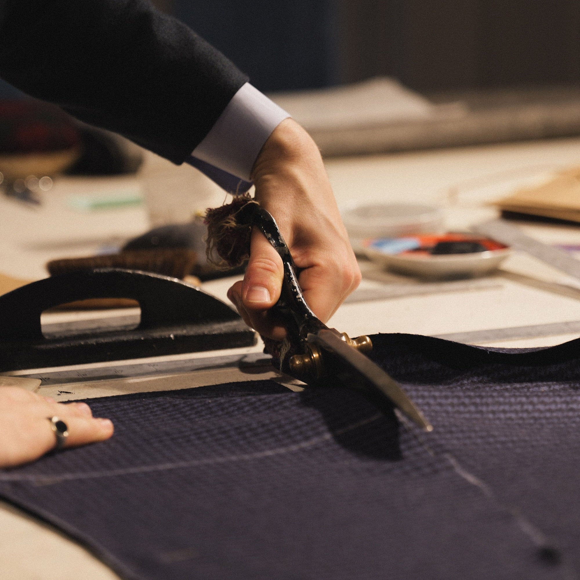 Person cutting fabric with scissors on a table