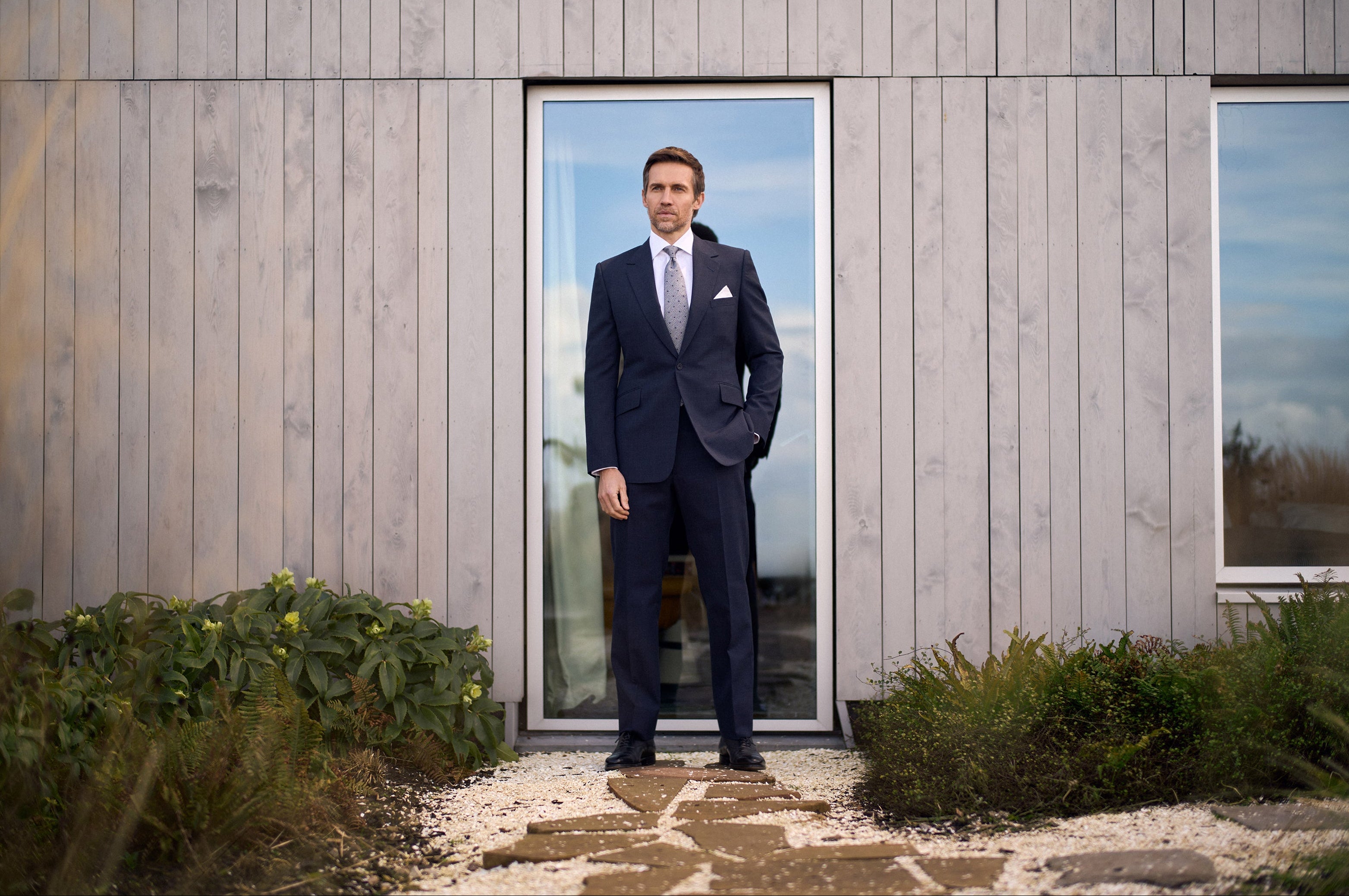 Model wearing the Huntsman indigo micro houndstooth single breasted suit from the Spring-Summer 2026 ready-to-wear collection