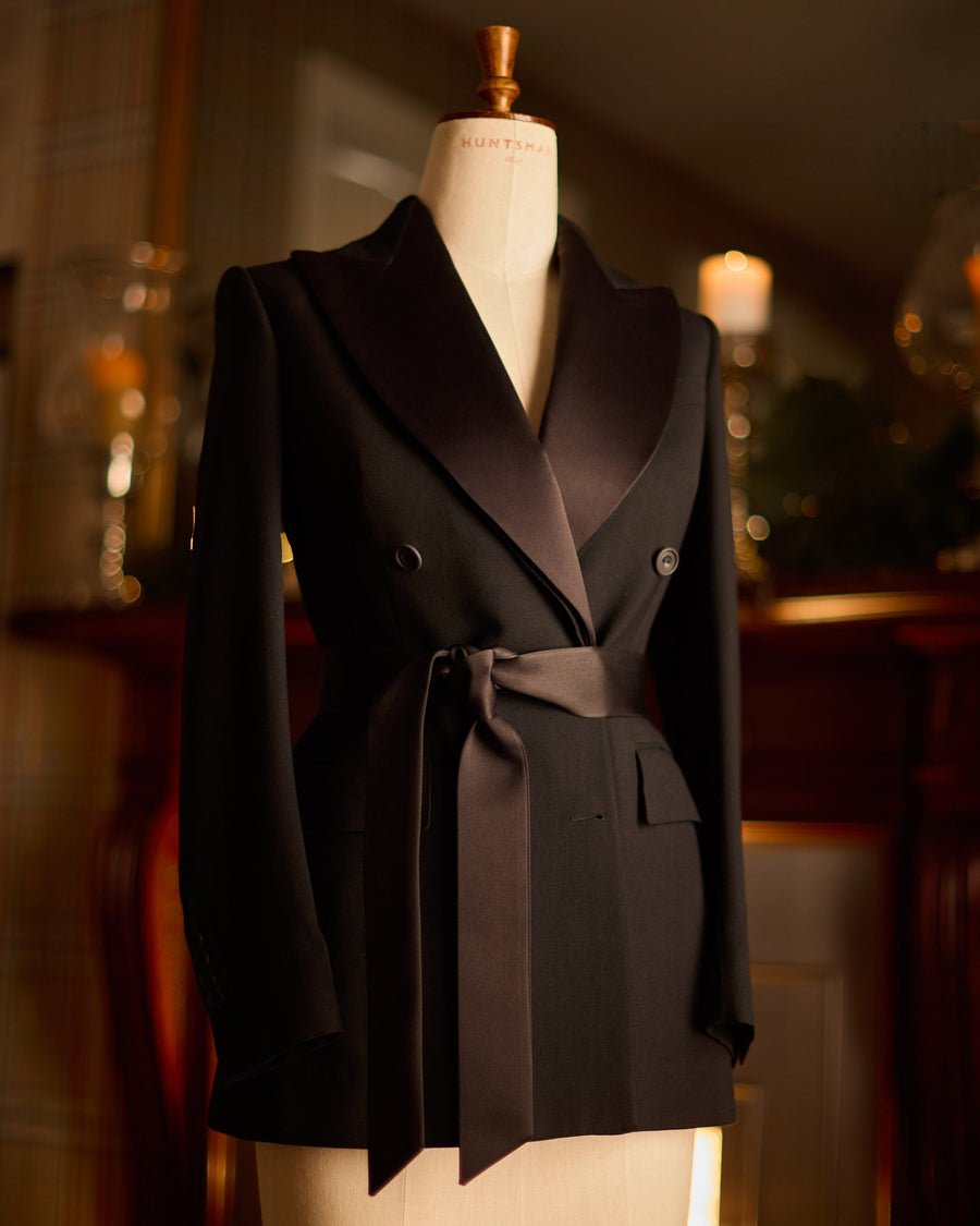 Huntsman ladies bespoke black double-breasted dinner jacket with tie belt, on mannequin.